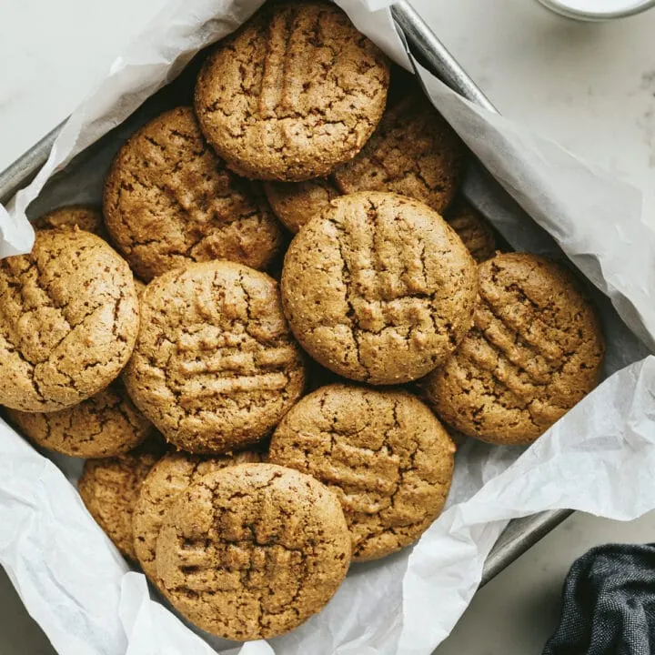 Almond flour peanut butter cookies in a cookie tin with white parchment paper.