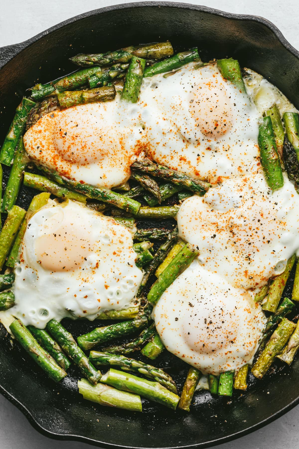 Asparagus and eggs in a black cast iron skillet.