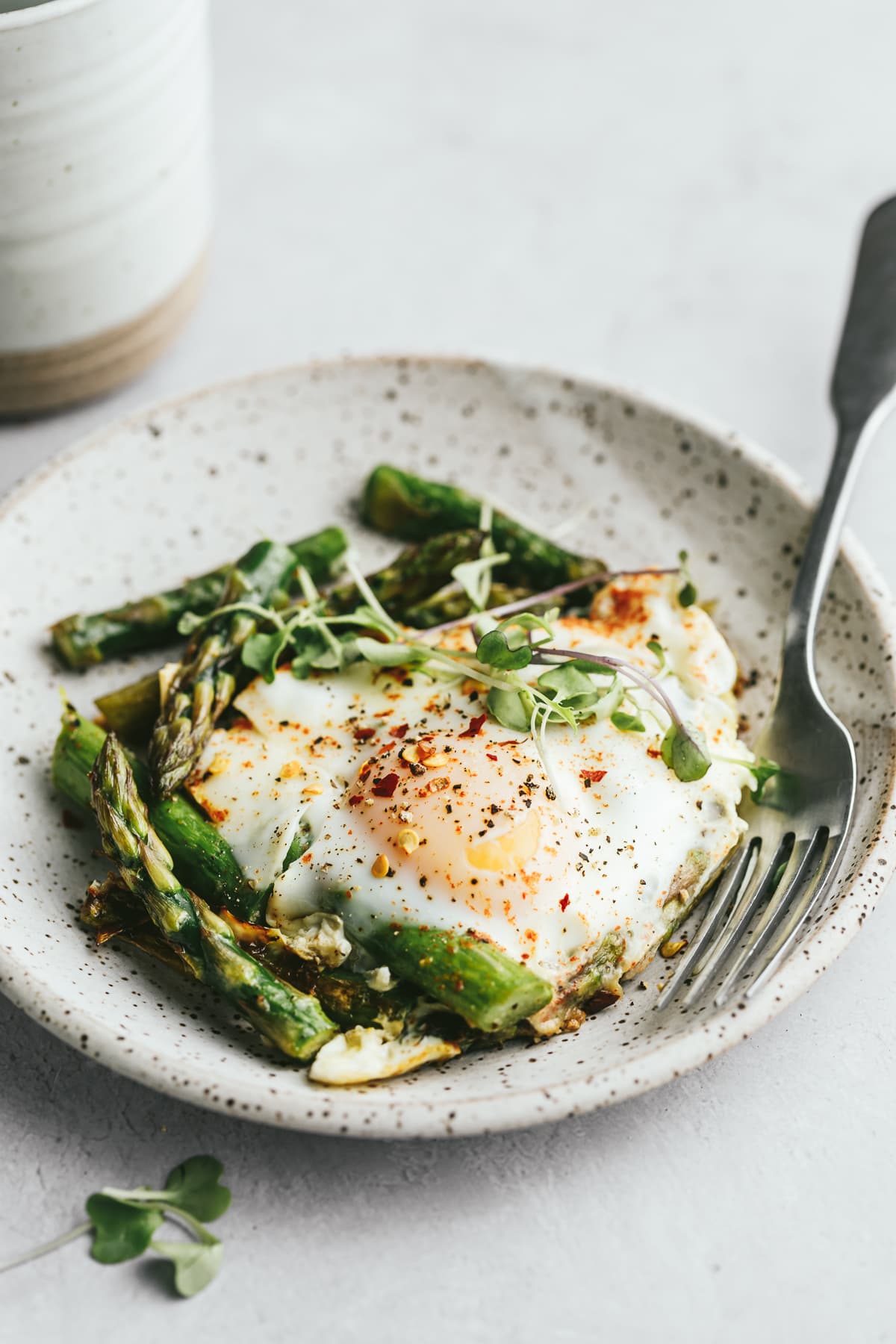 Asparagus and eggs on a speckled plate with a fork.