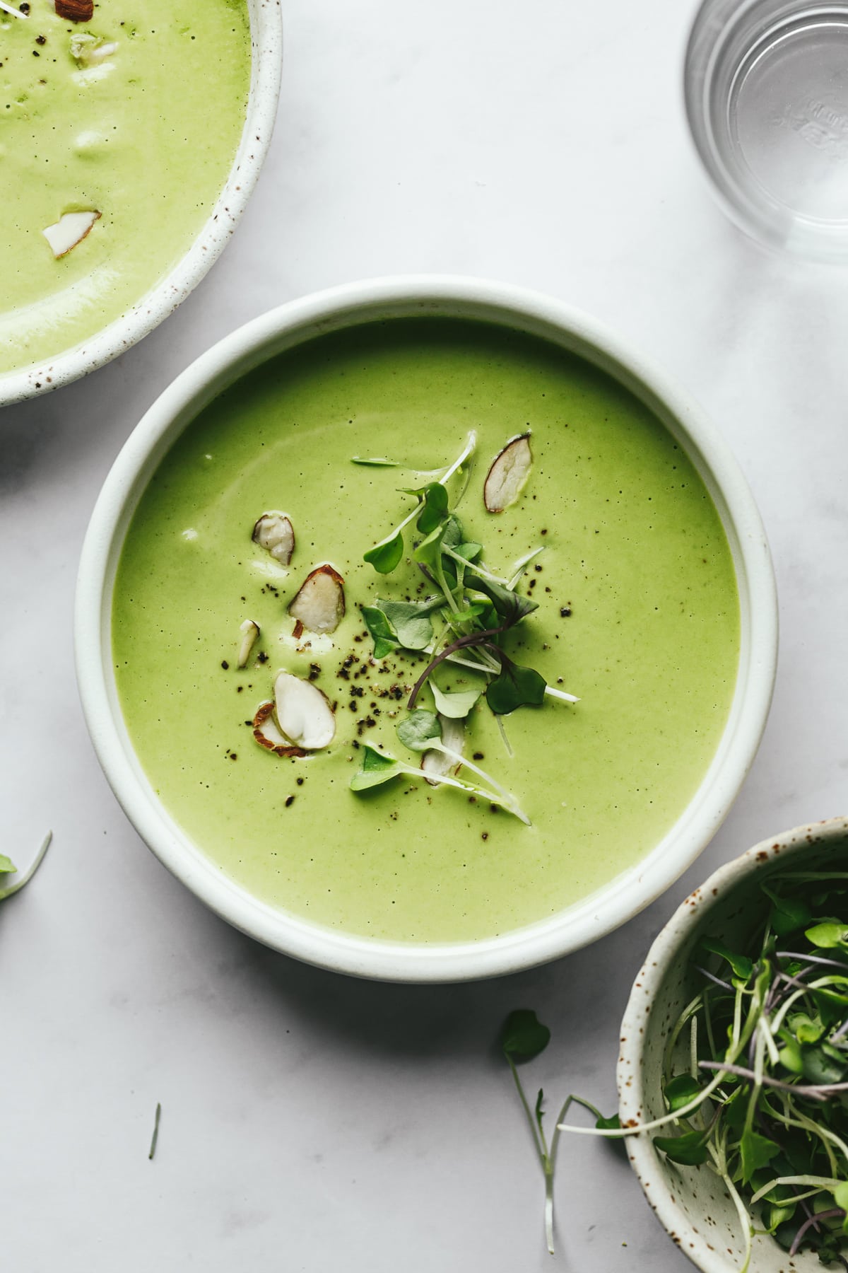 Closeup of a bowl of broccoli almond soup with garnishes.