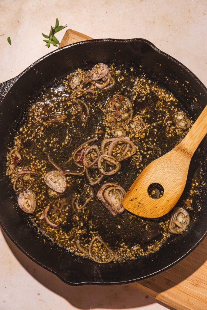 A large cast iron skillet with garlic and shallots.