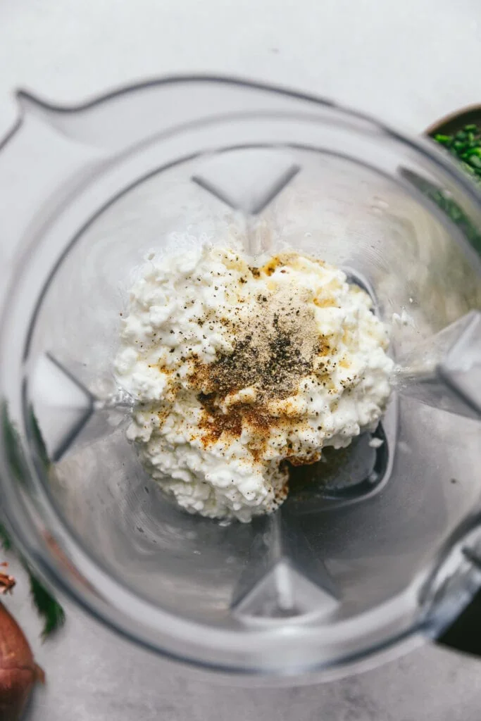 A blender with cottage cheese and spices.