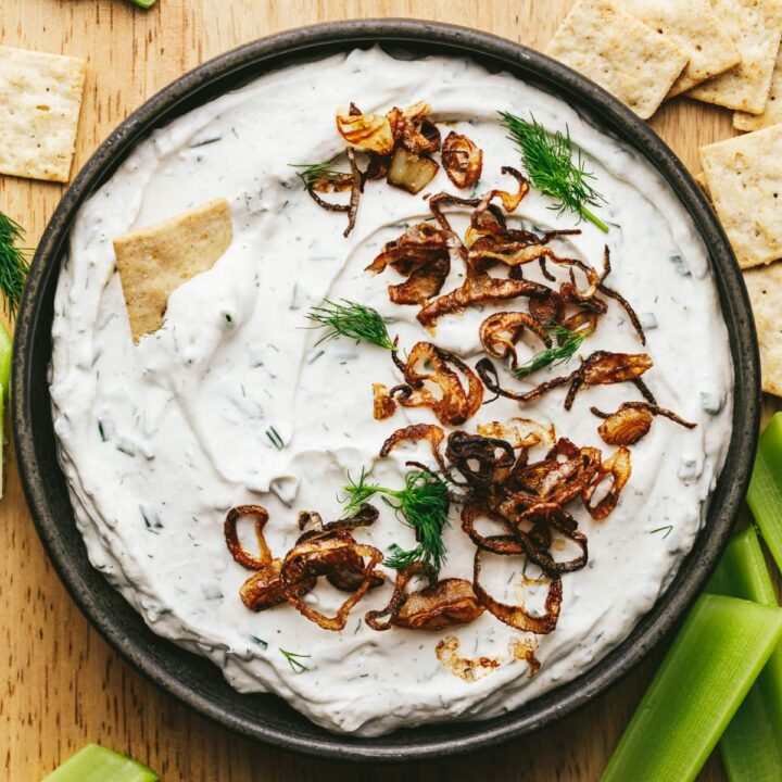 A black bowl with cottage cheese dip and shallots.