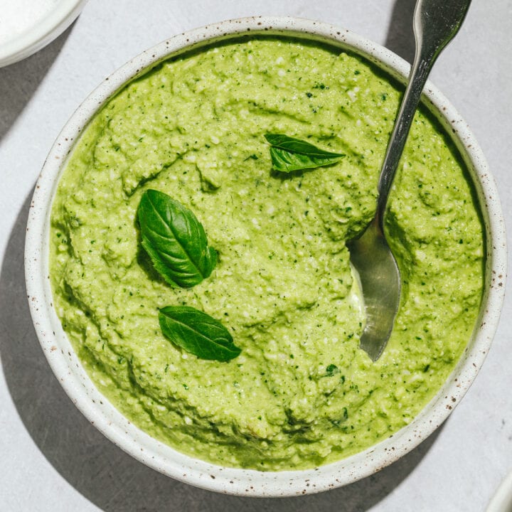 Zucchini pesto in a white bowl with a spoon.