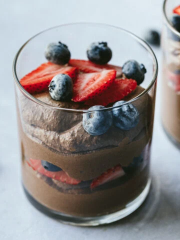 Closeup of blended chia pudding in a glass dish with fresh berries.