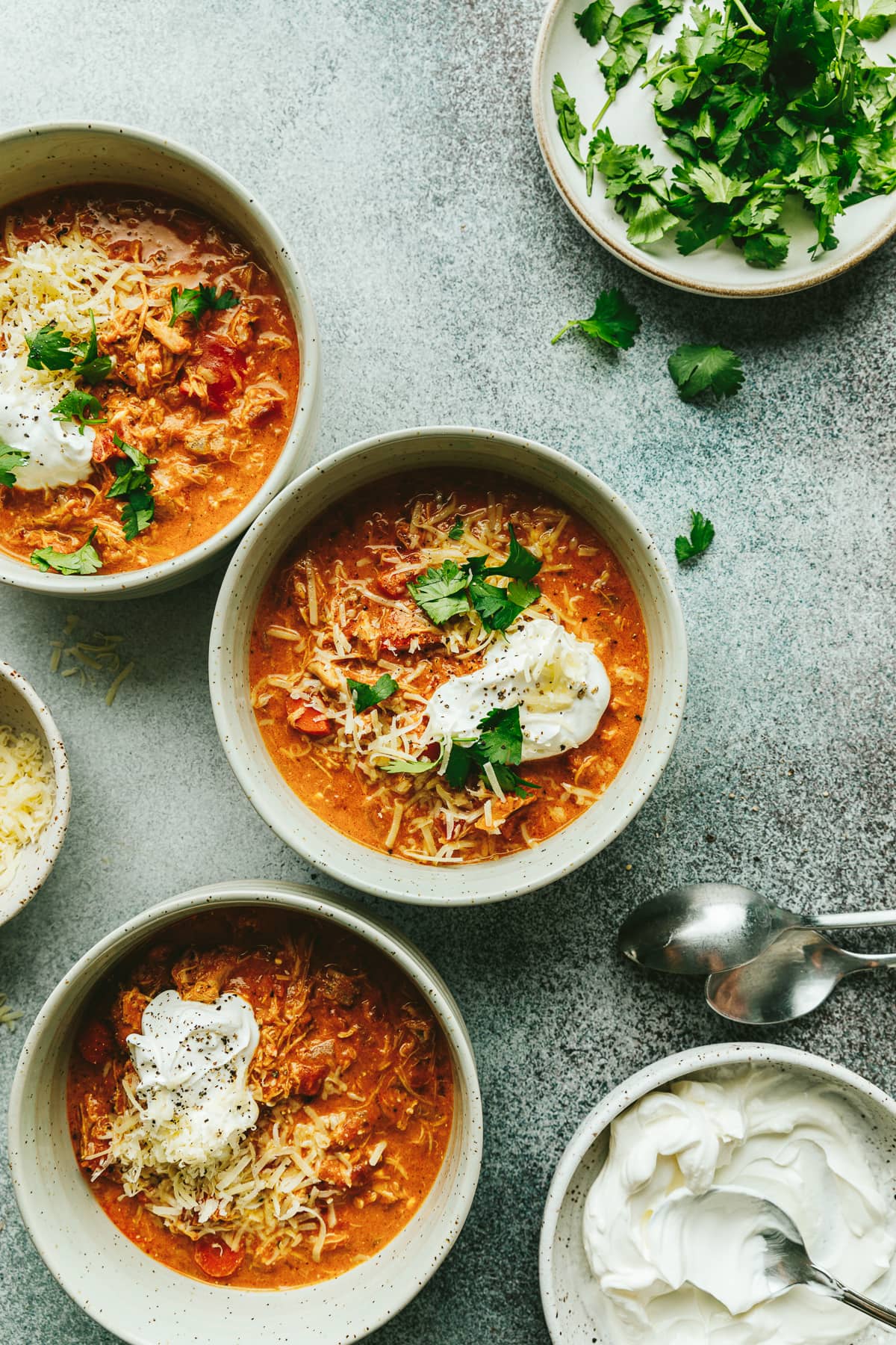 Crockpot pumpkin chili in bowls with garnishes and toppings.