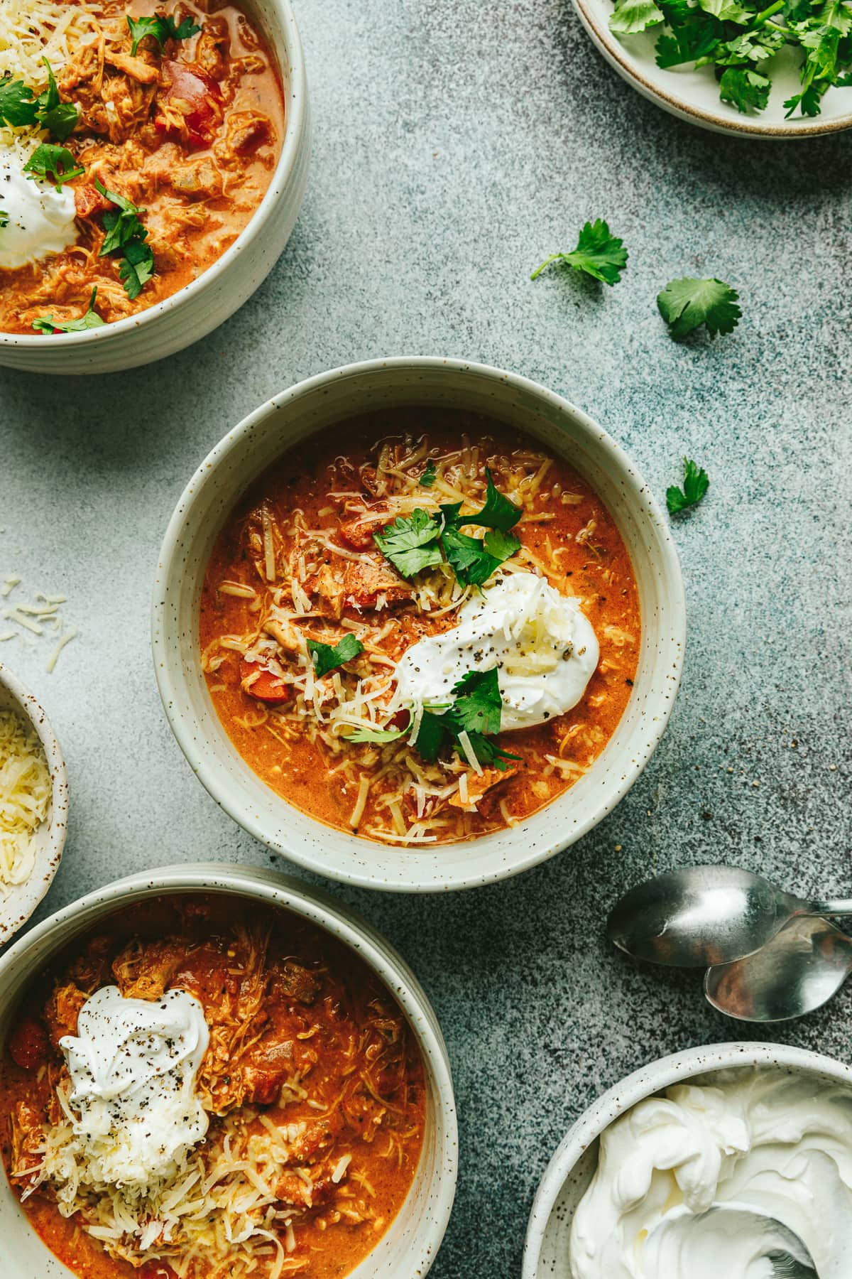 Keto Crockpot pumpkin chili dished into three speckled bowls with toppings.