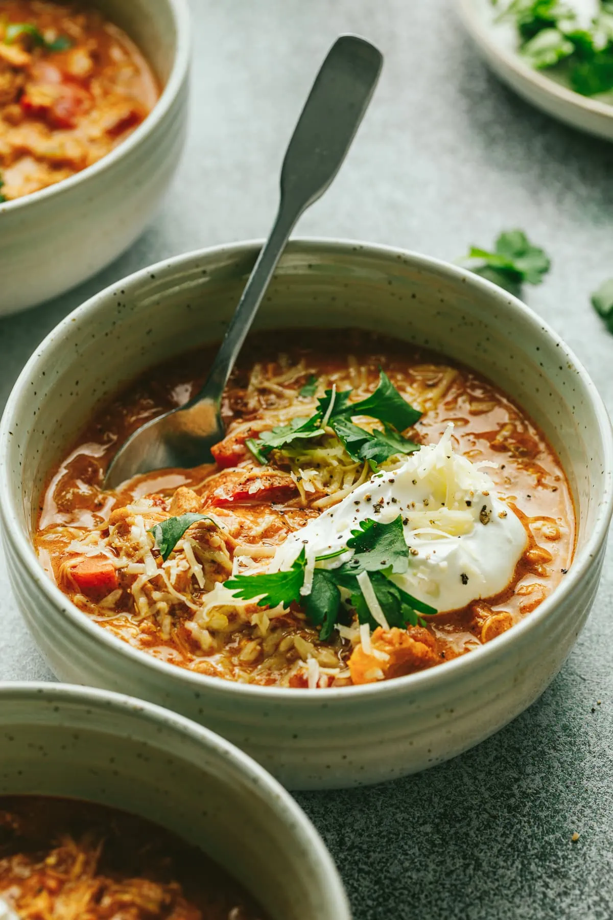 A bowl of keto pumpkin chicken chili with a spoon and sour cream.