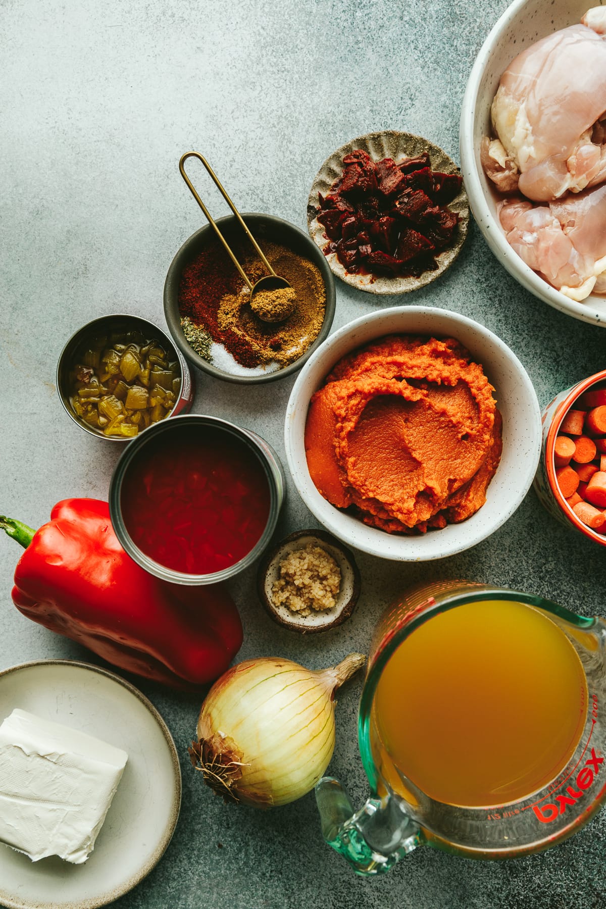 Ingredients for crockpot pumpkin chili on a light aqua surface.