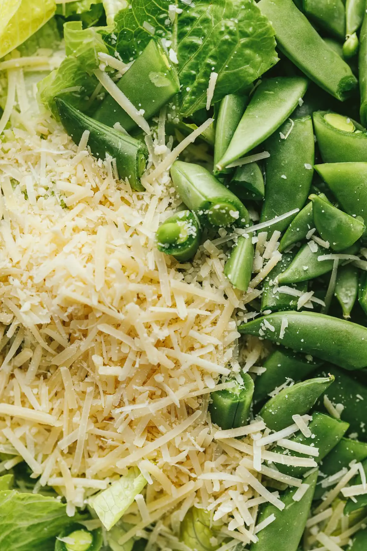 Closeup of Parmesan cheese, snap peas and romaine lettuce for sirloin caesar salad.