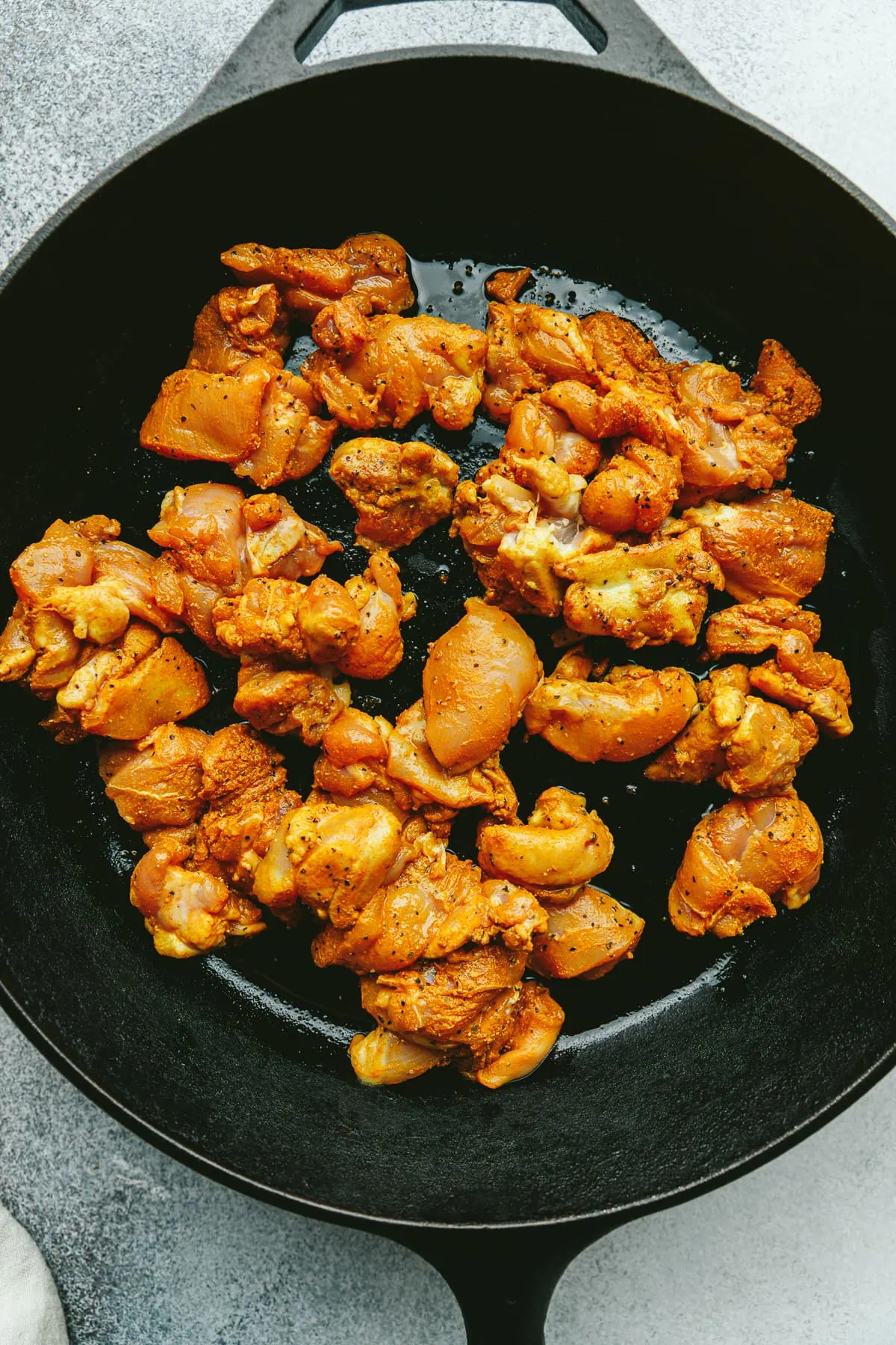 Chicken thighs seasoned in turmeric black pepper in a cast iron skillet.