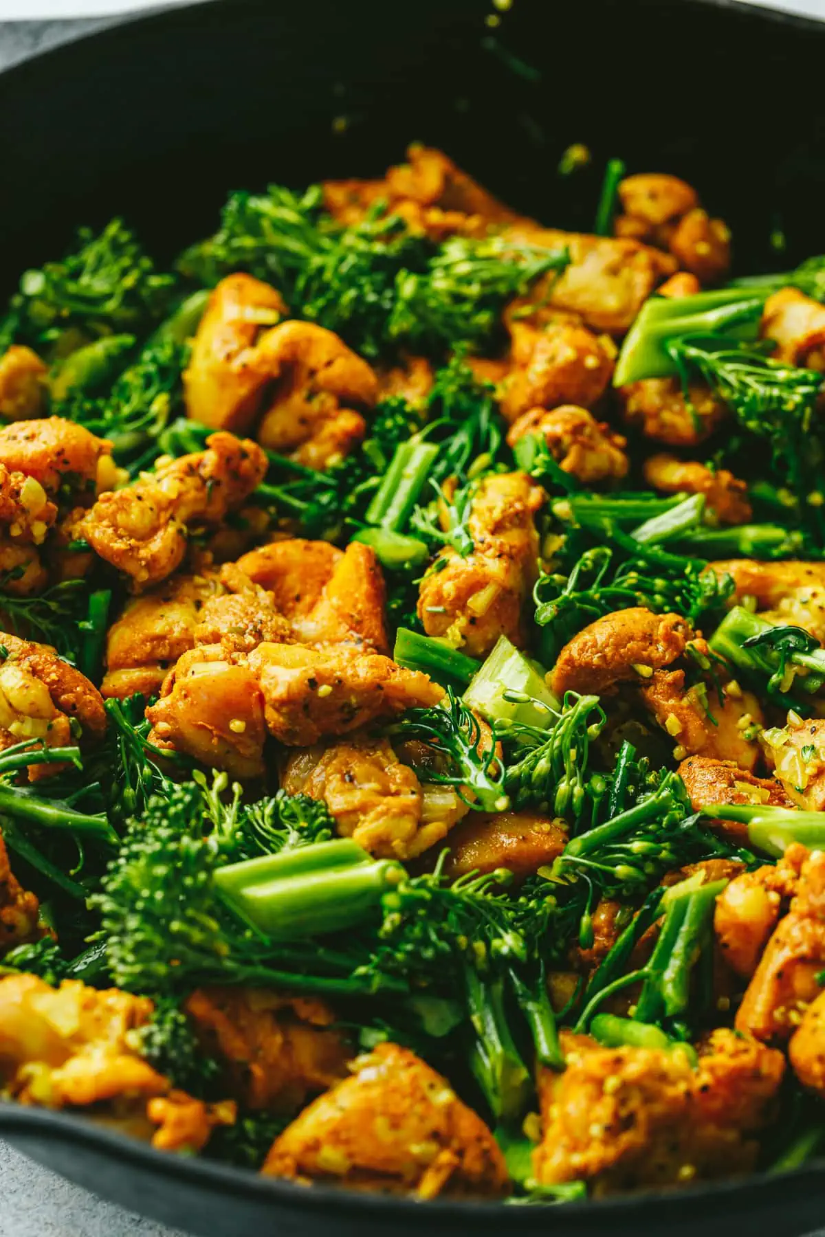 Broccolini and chicken in a skillet.