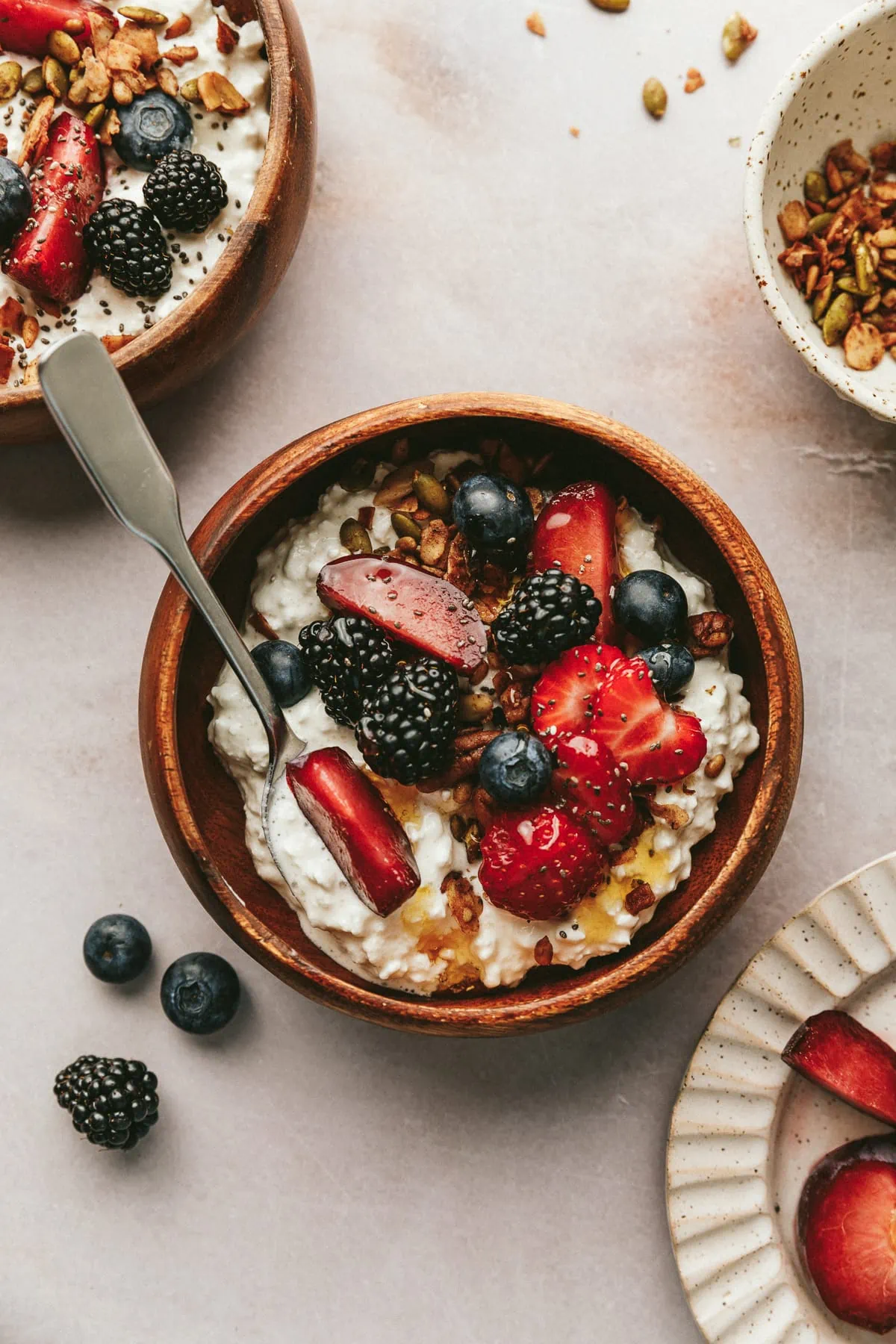 Overhead shot of a wooden bowls with cottage cheese, fruit, honey and keto granola.