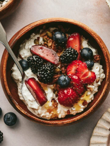 Cottage cheese with fruit in a wooden bowl with a spoon.
