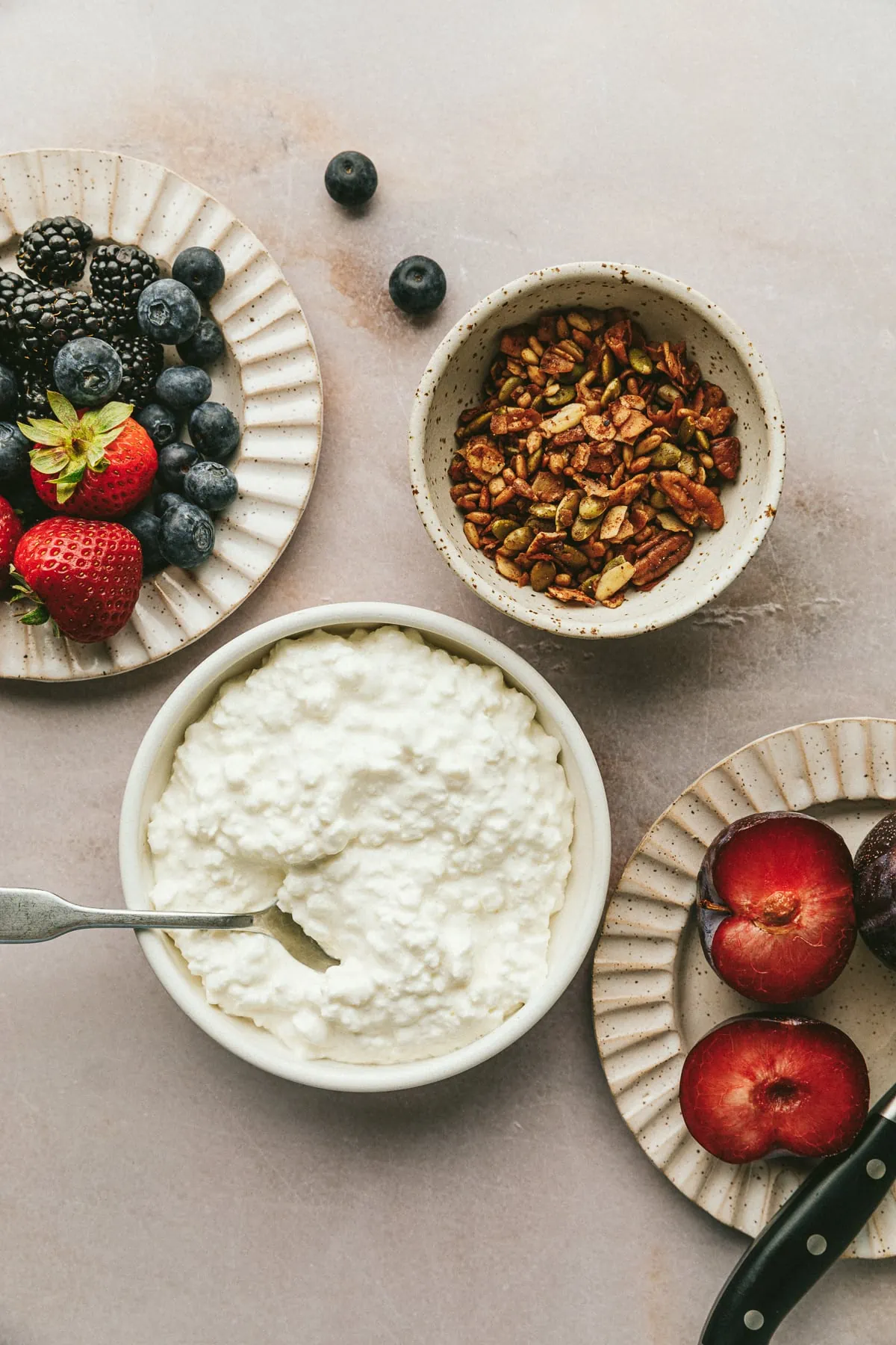 Ingredients for cottage cheese with fruit on a marble surface.