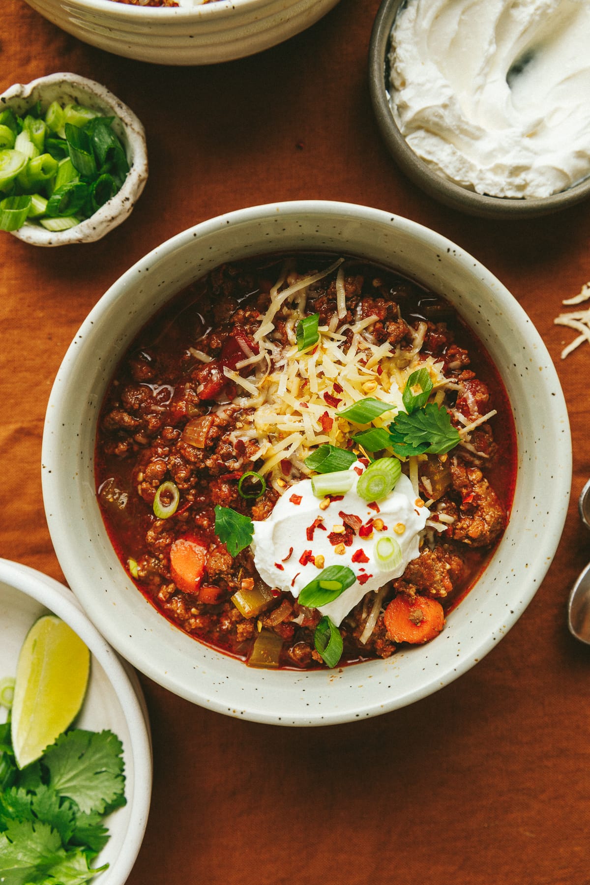 A bowl of Crockpot no bean chili surrounded by different toppings.