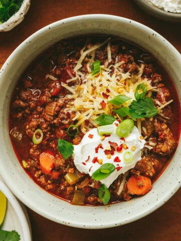 Closeup of a single bowl of Crockpot no bean chili topped with garnishes.