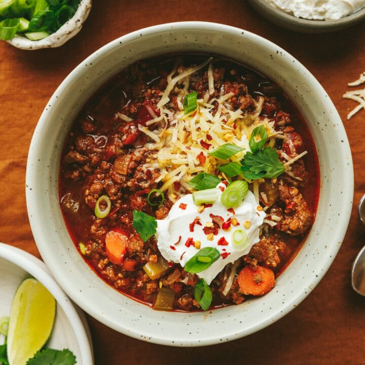Closeup of a single bowl of Crockpot no bean chili topped with garnishes.