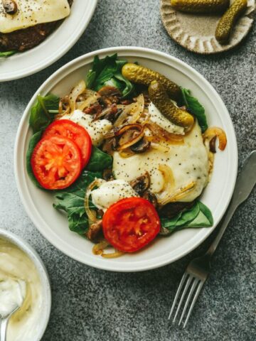 Closeup of a healthy burger bowl with burger toppings on a gray surface.