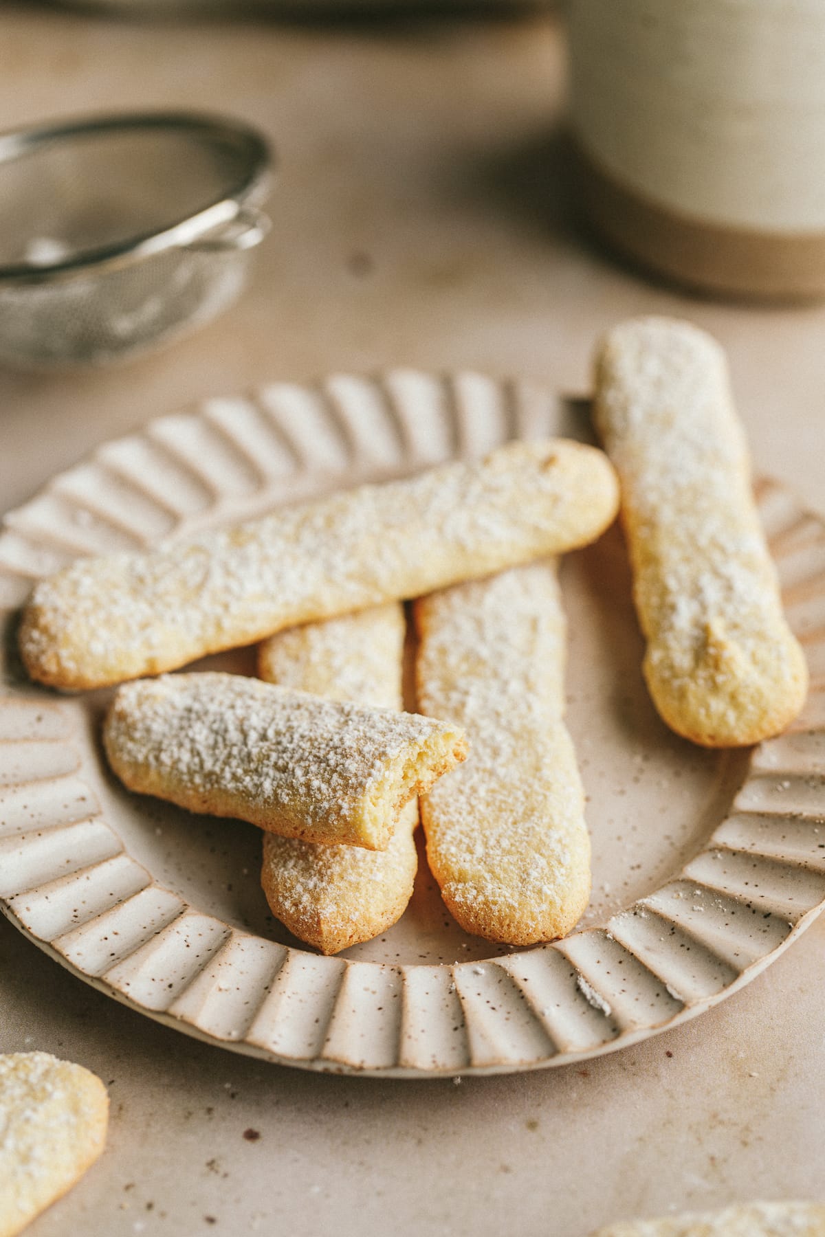 Keto ladyfingers on a plate with a coffee cup in the background.