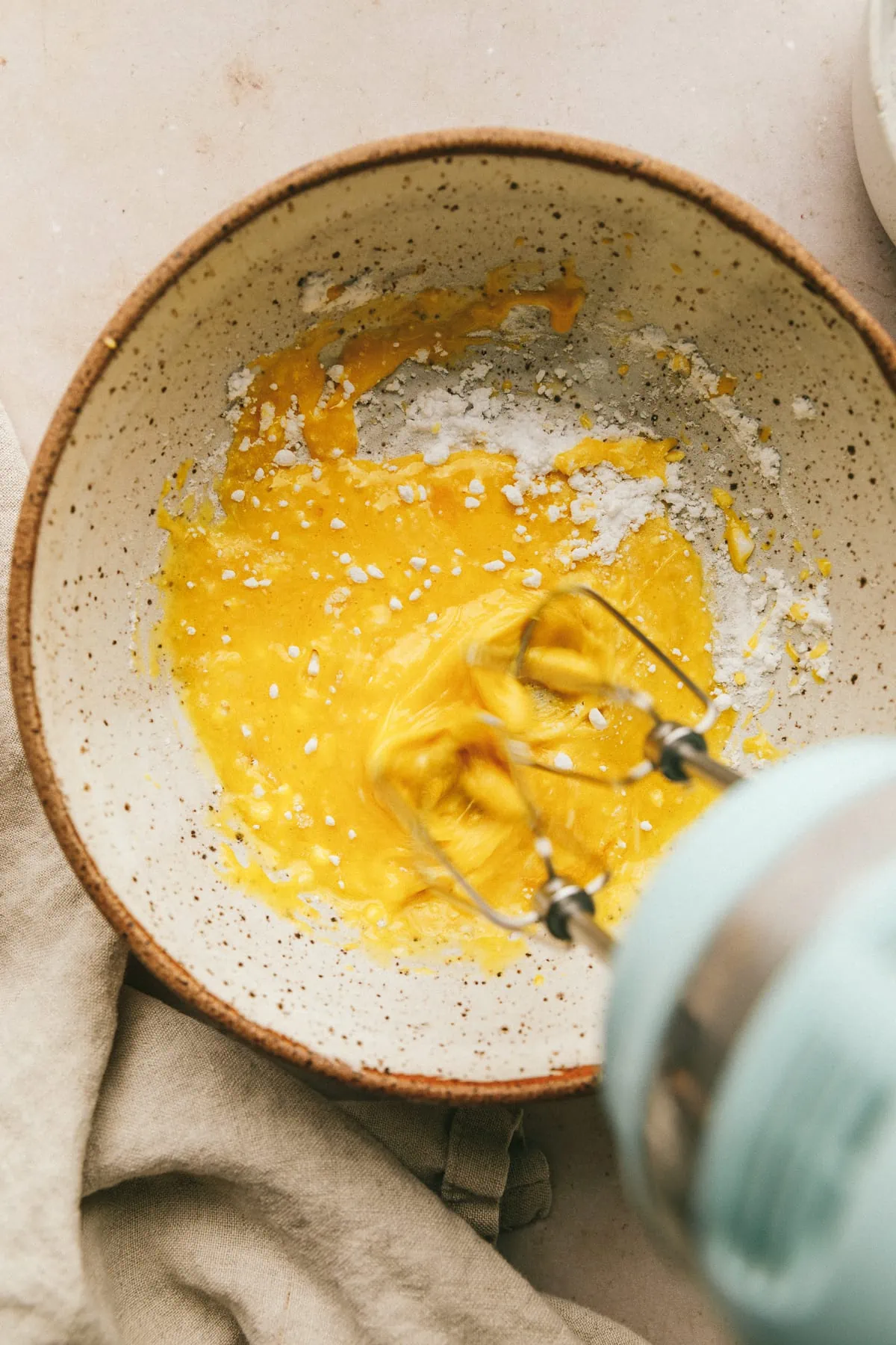 Hand mixer beating egg yolks with powdered monk fruit sweetener for keto ladyfingers recipe.