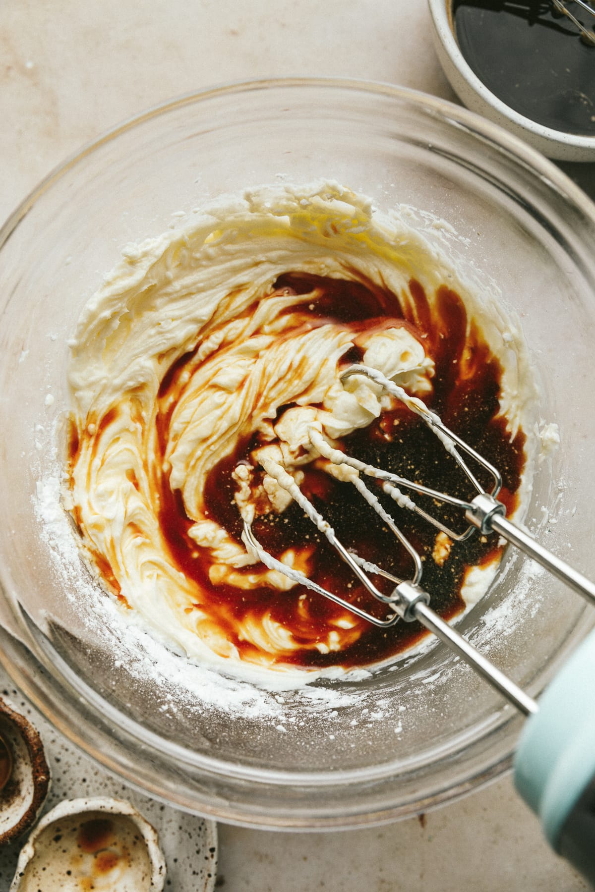 Mixing coffee mixture into mascarpone with an electric mixer.