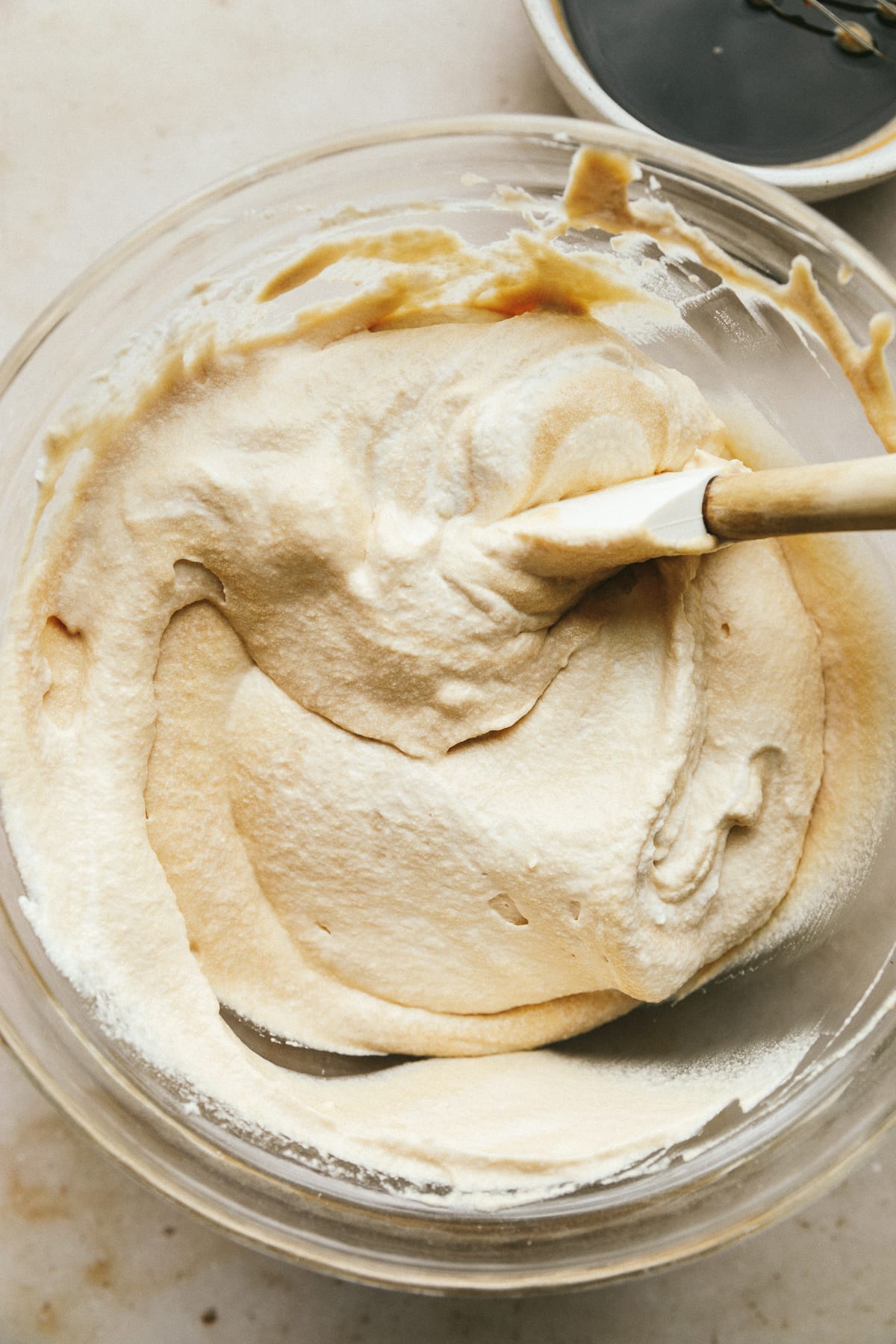 Folding mascarpone and whipped cream in a mixing bowl.