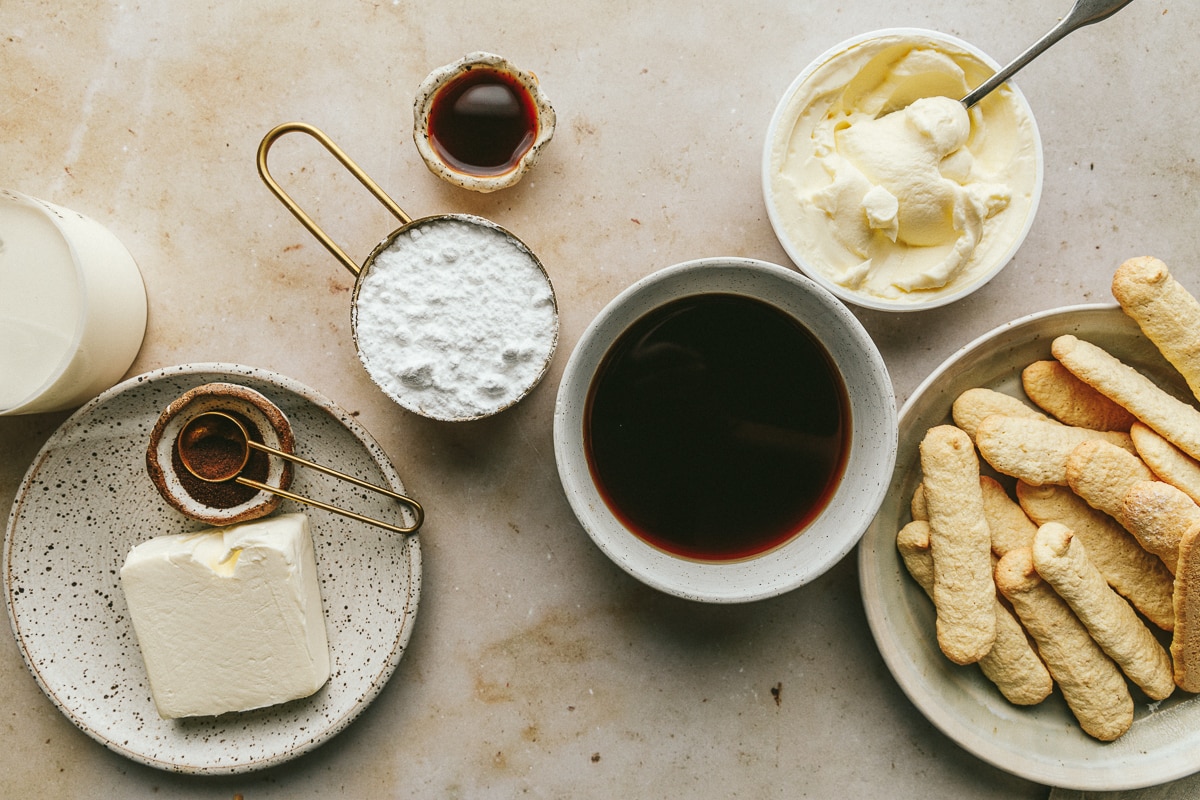 Ingredients for keto tiramisu arranged on a beige marble surface.