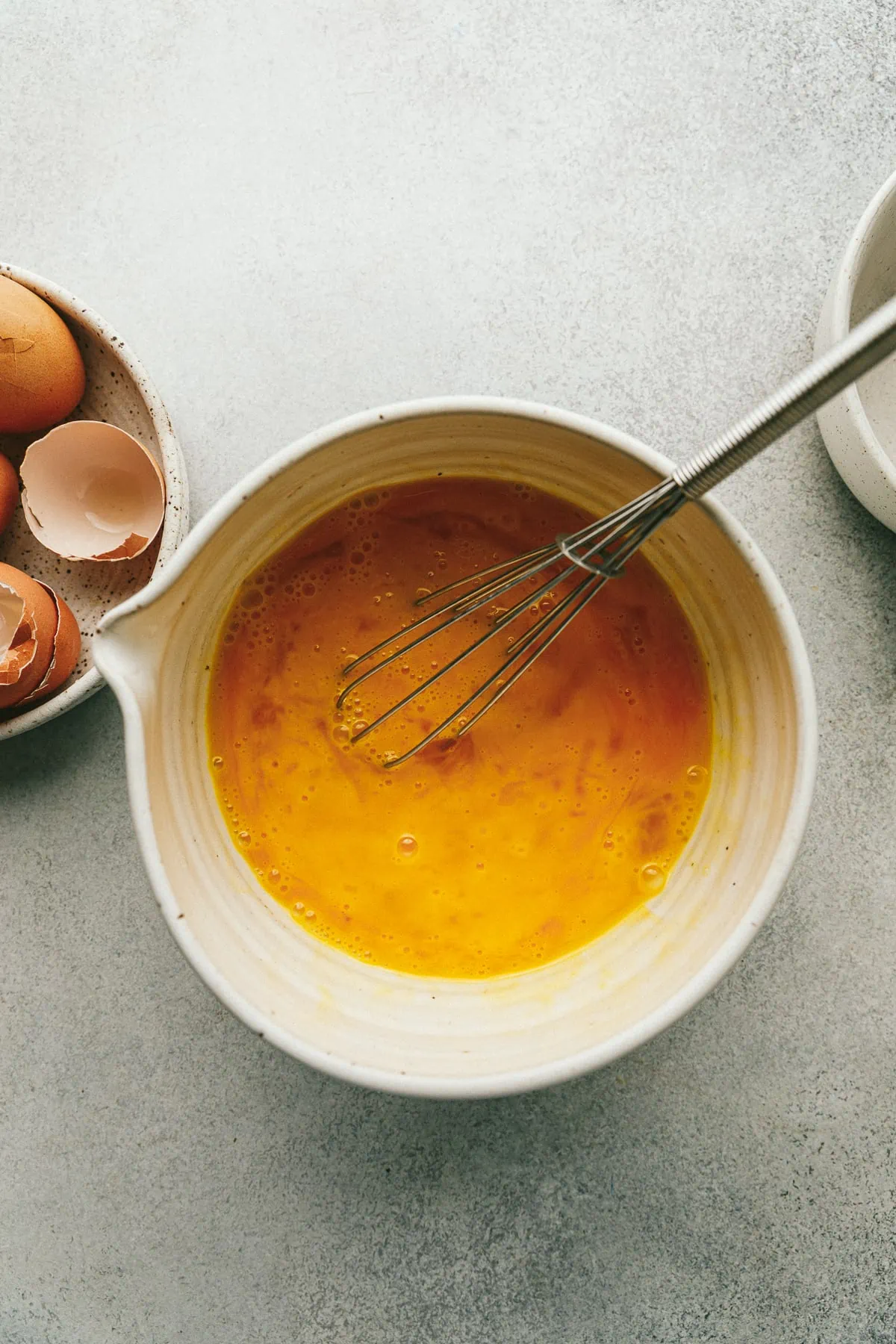 Cracked eggs in a small bowl with a whisk.