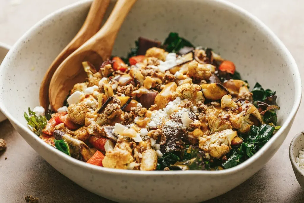 A salad bowl with fall kale salad and pumpkin vinaigrette.