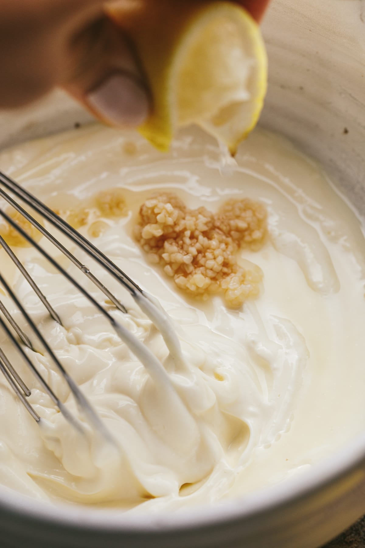 Squeezing lemon juice into a bowl with mayo and garlic for truffle aioli.