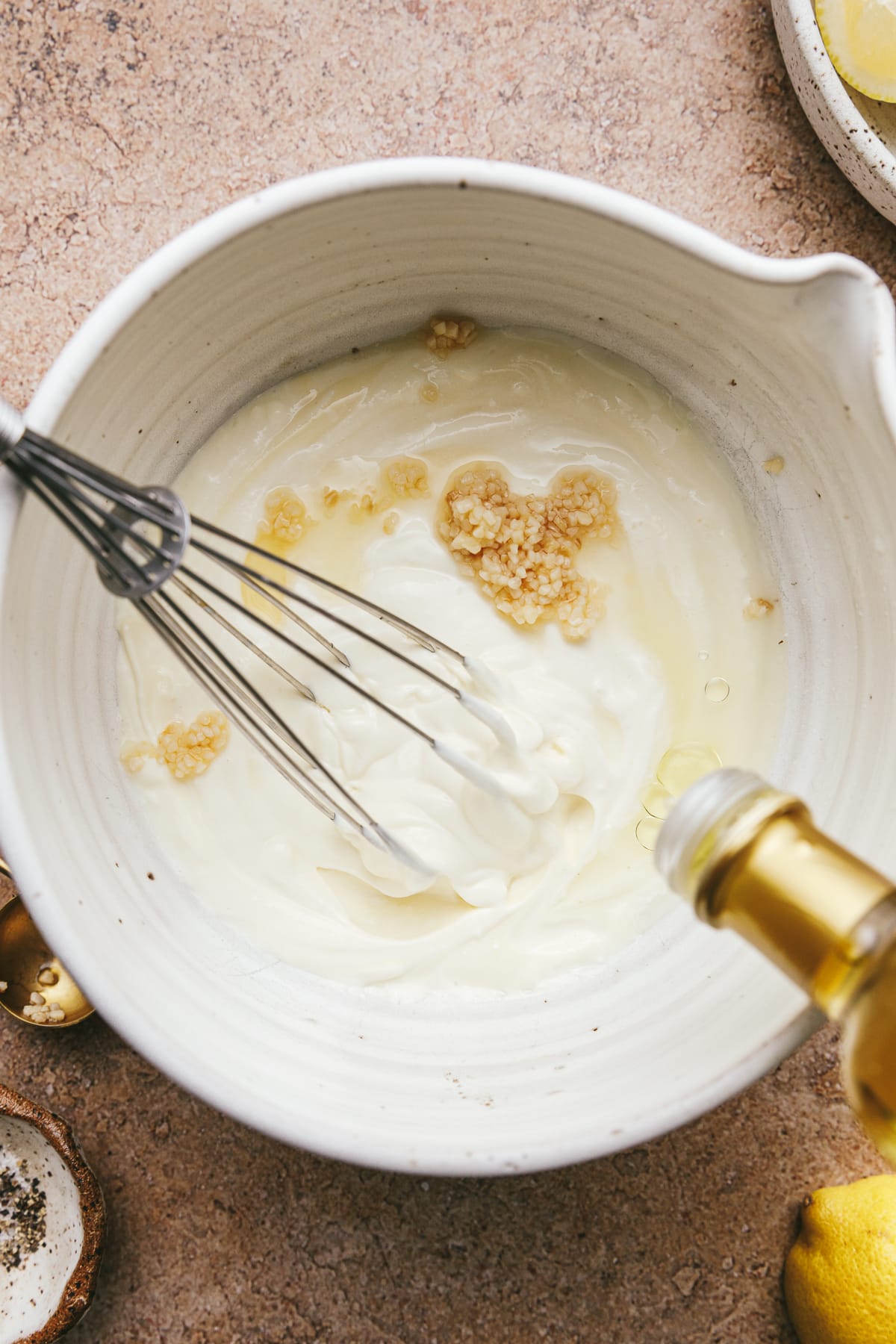Dropping black truffle oil into a bowl with other ingredients to make truffle aioli.