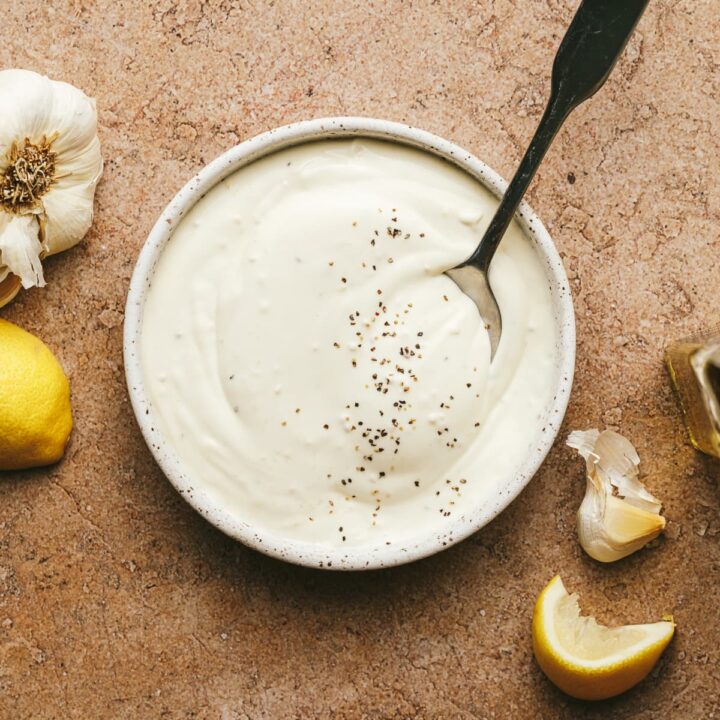 A small dish with black truffle aioli and a spoon.