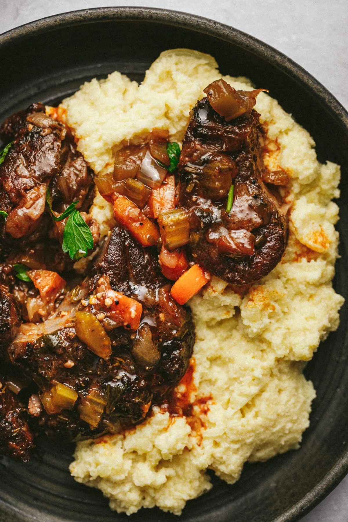 Closeup of braised beef shanks on cauliflower mash.