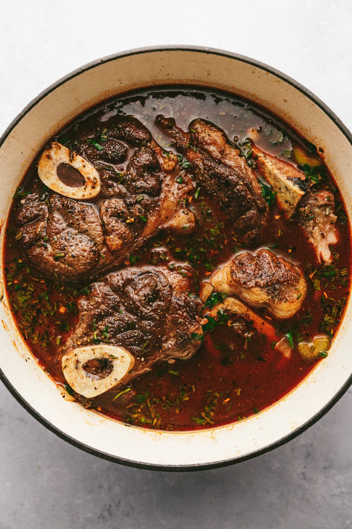 Beef shanks in a Dutch oven with braising liquid.