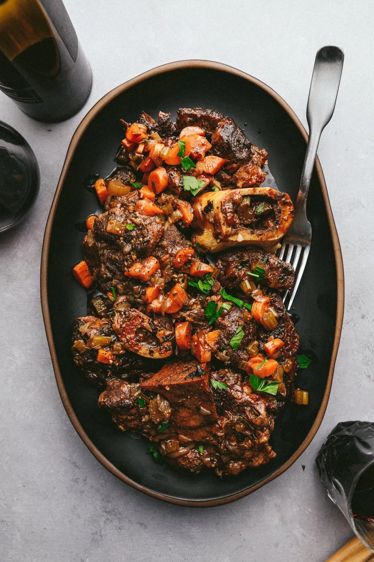 A serving platter with braised beef shanks and a fork.