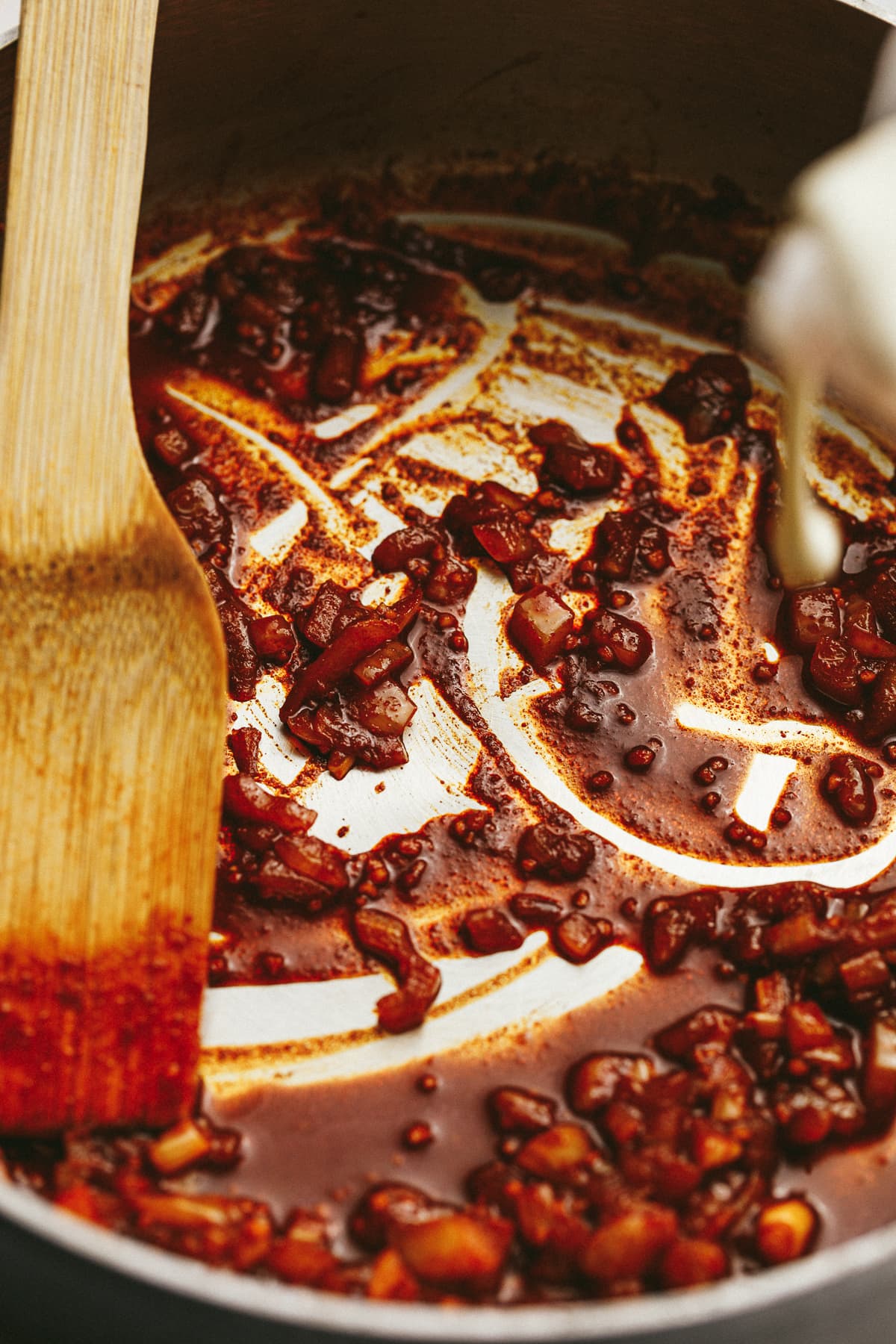 Pouring cream into pan with onions and paprika and garlic.