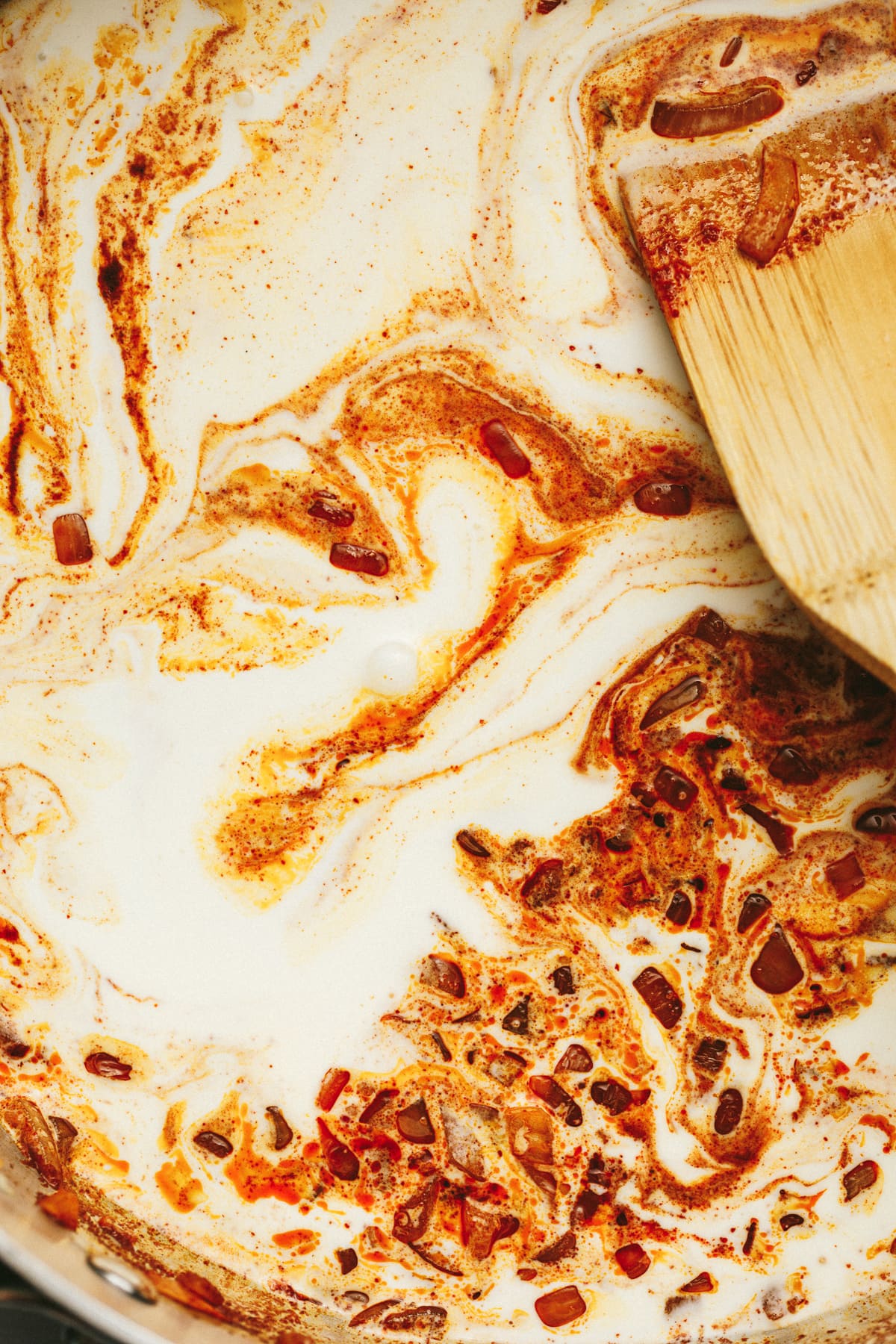 Closeup of the cream being mixed into the paprika sauce.
