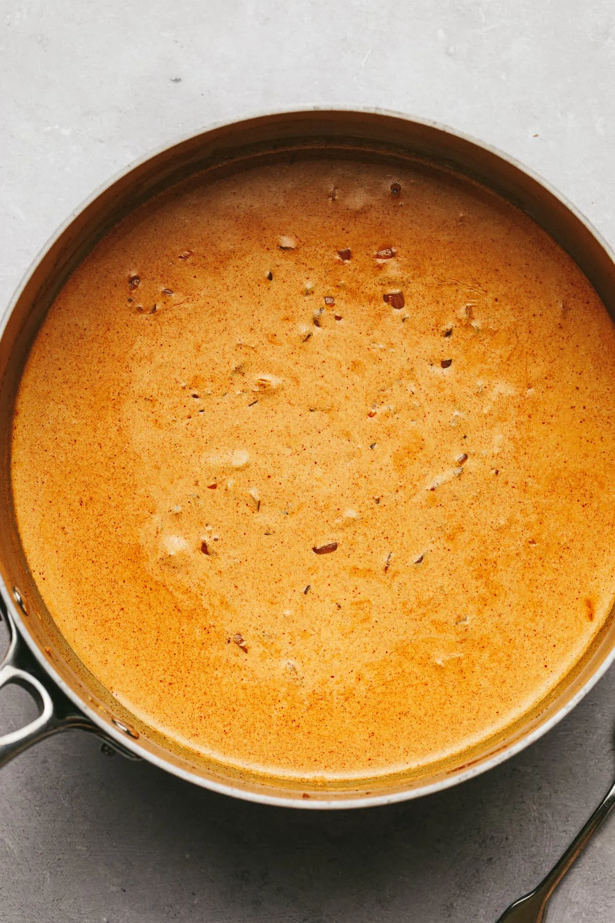 Paprika sauce in a stainless steal pan on a gray surface.