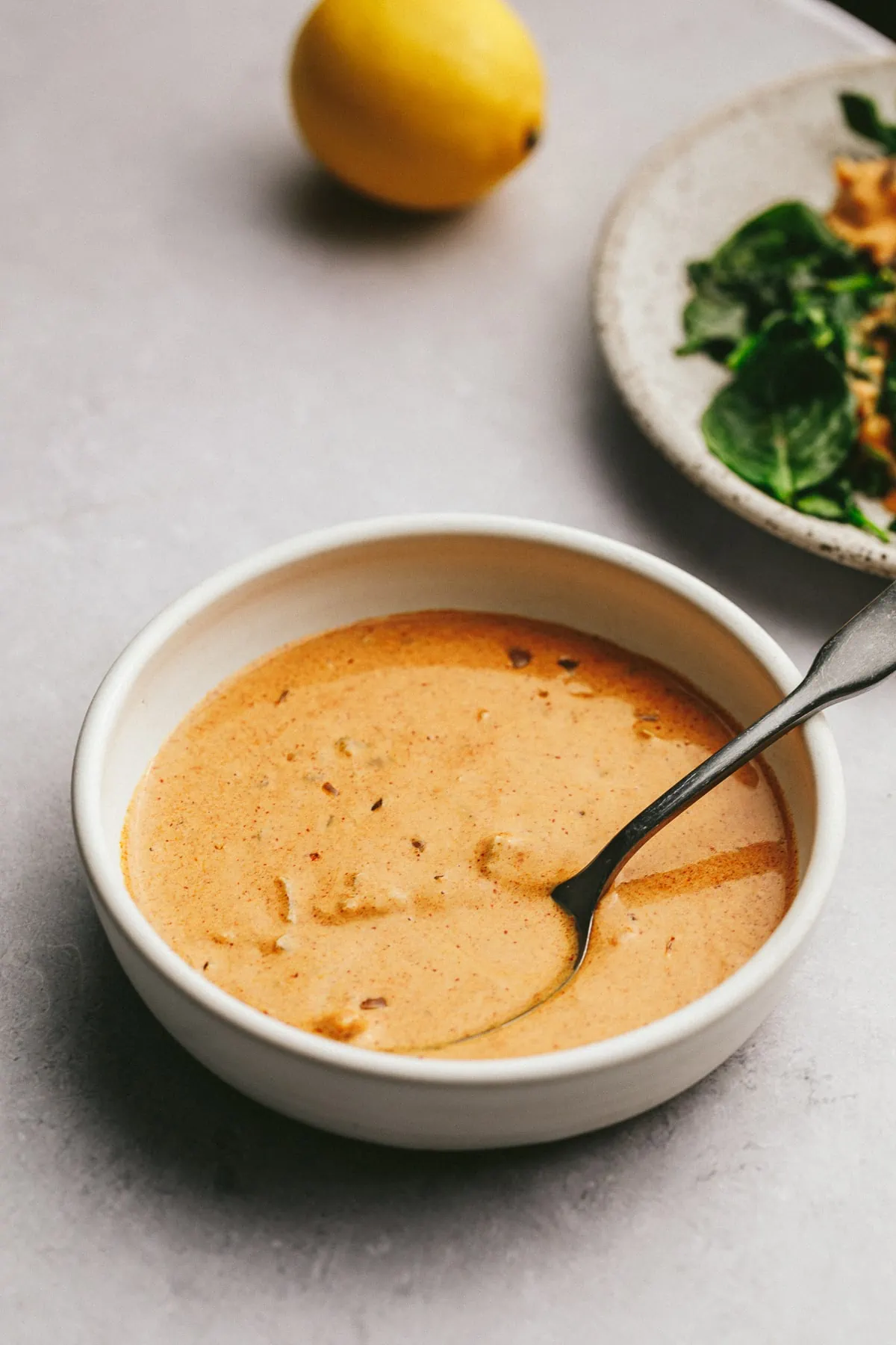 Paprika sauce in a small white bowl with a dish behind it.