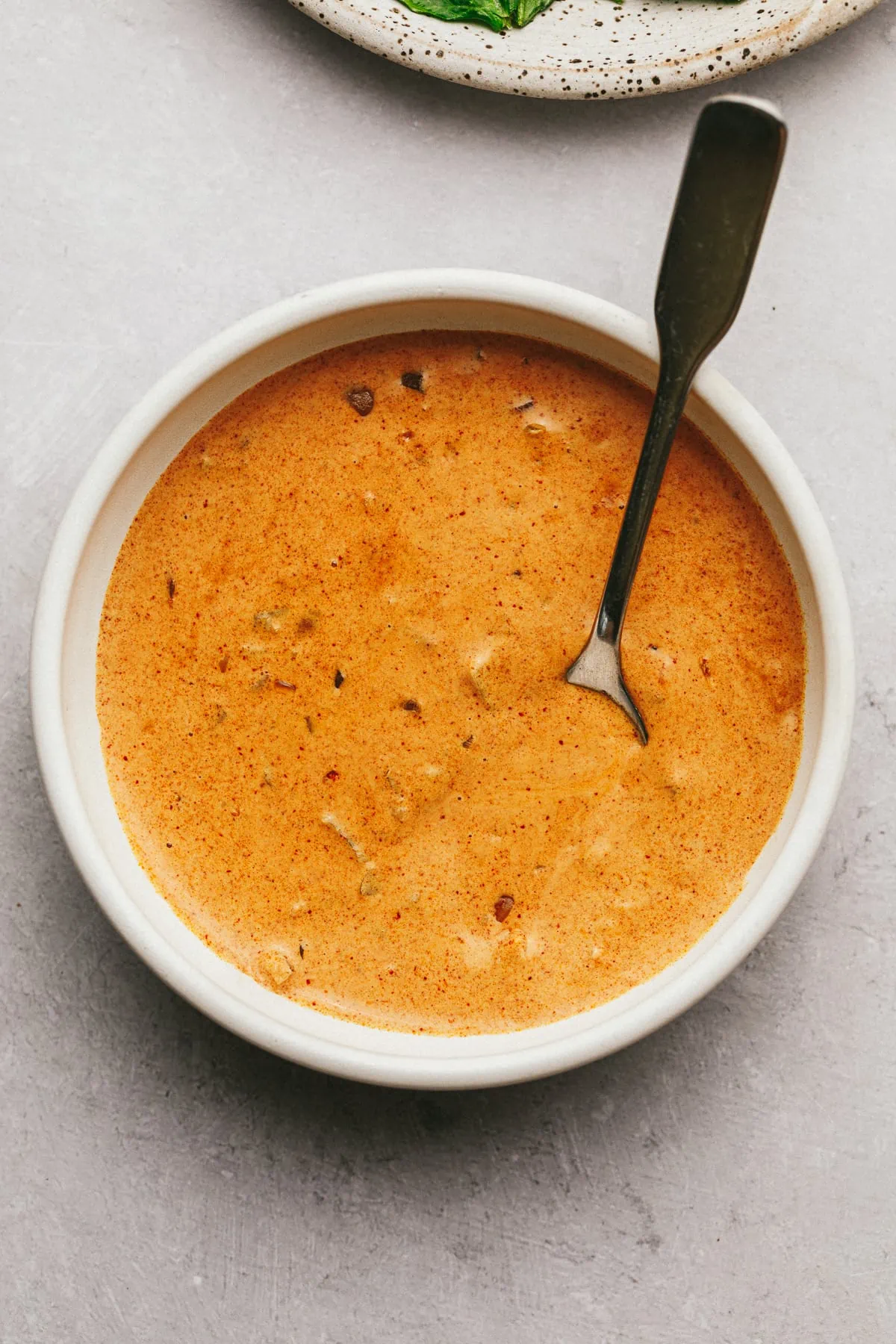 Paprika sauce in a small white bowl with a serving spoon.