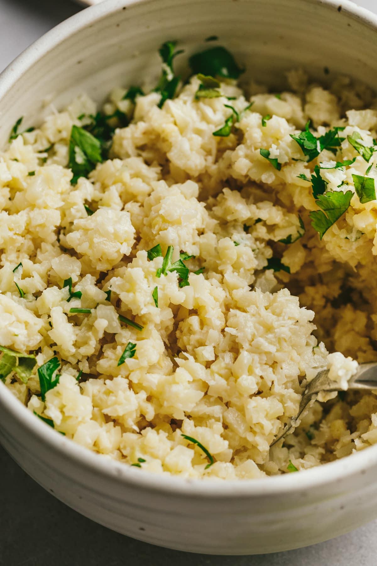 Coconut cauli rice being dished up with a spoon.