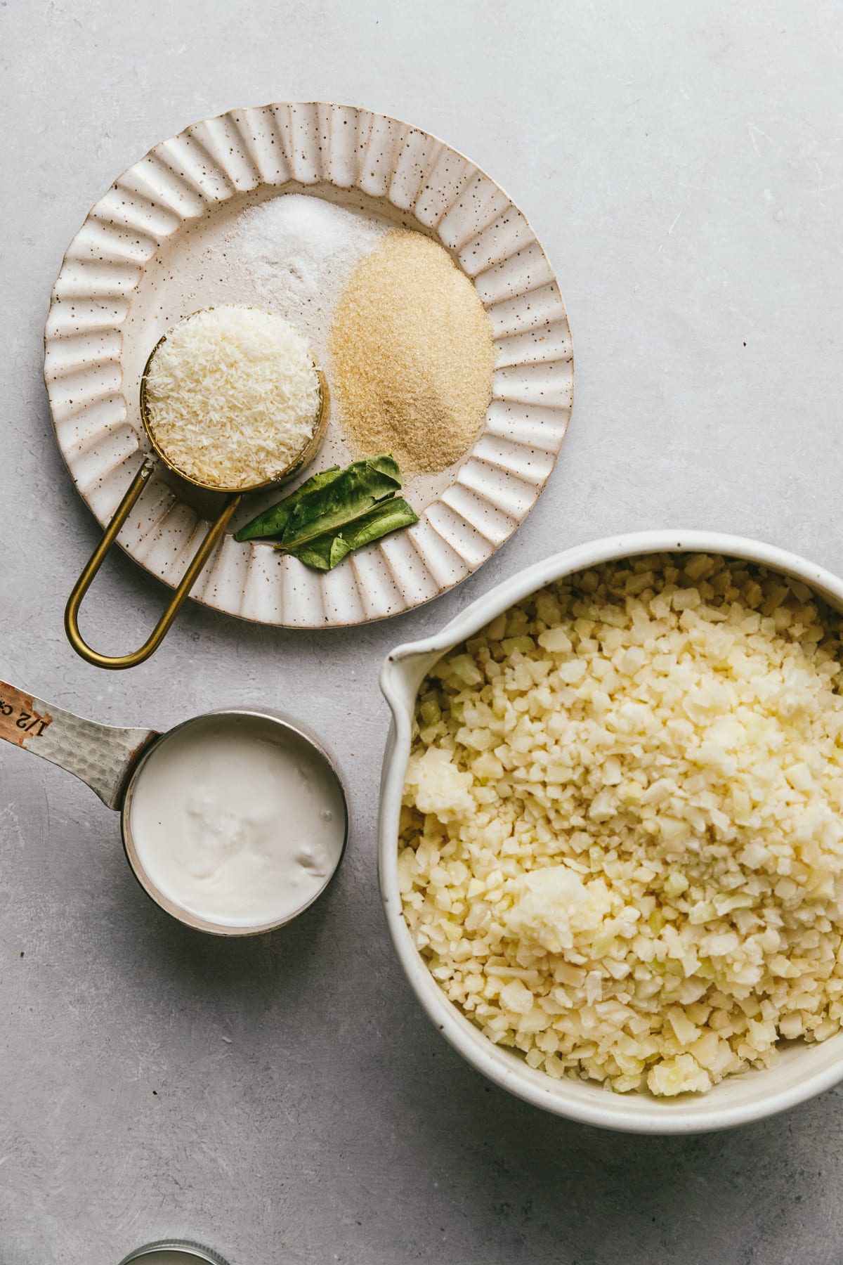 Cauliflower rice, monk fruit sweetener and coconut cream arranged to show ingredients for coconut cauliflower rice.