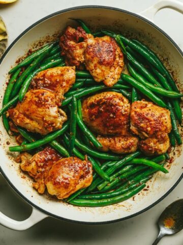 Chicken thighs with green beans in a braiser pan.
