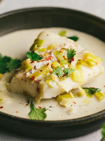A piece of keto cod in coconut milk and garnishes.