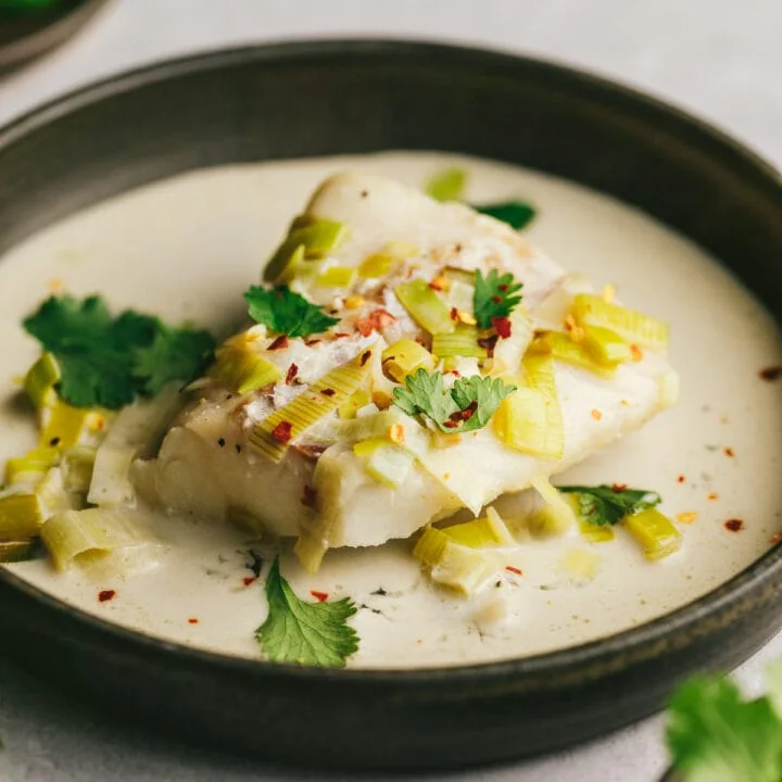 A piece of keto cod in coconut milk and garnishes.