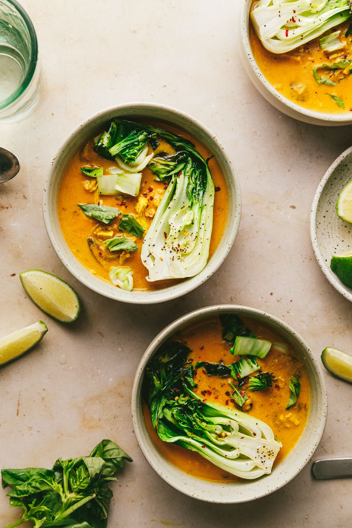 A tablescape with three bowls of keto red curry and garnishes.