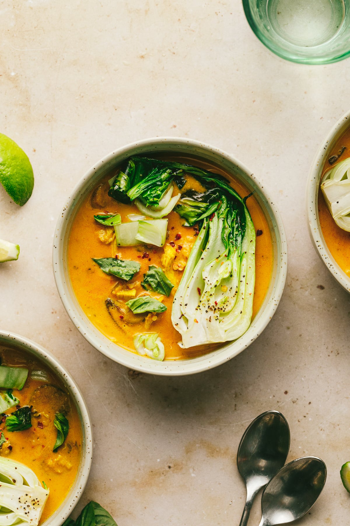 Three bowls of keto chicken curry soup on a marble surface.