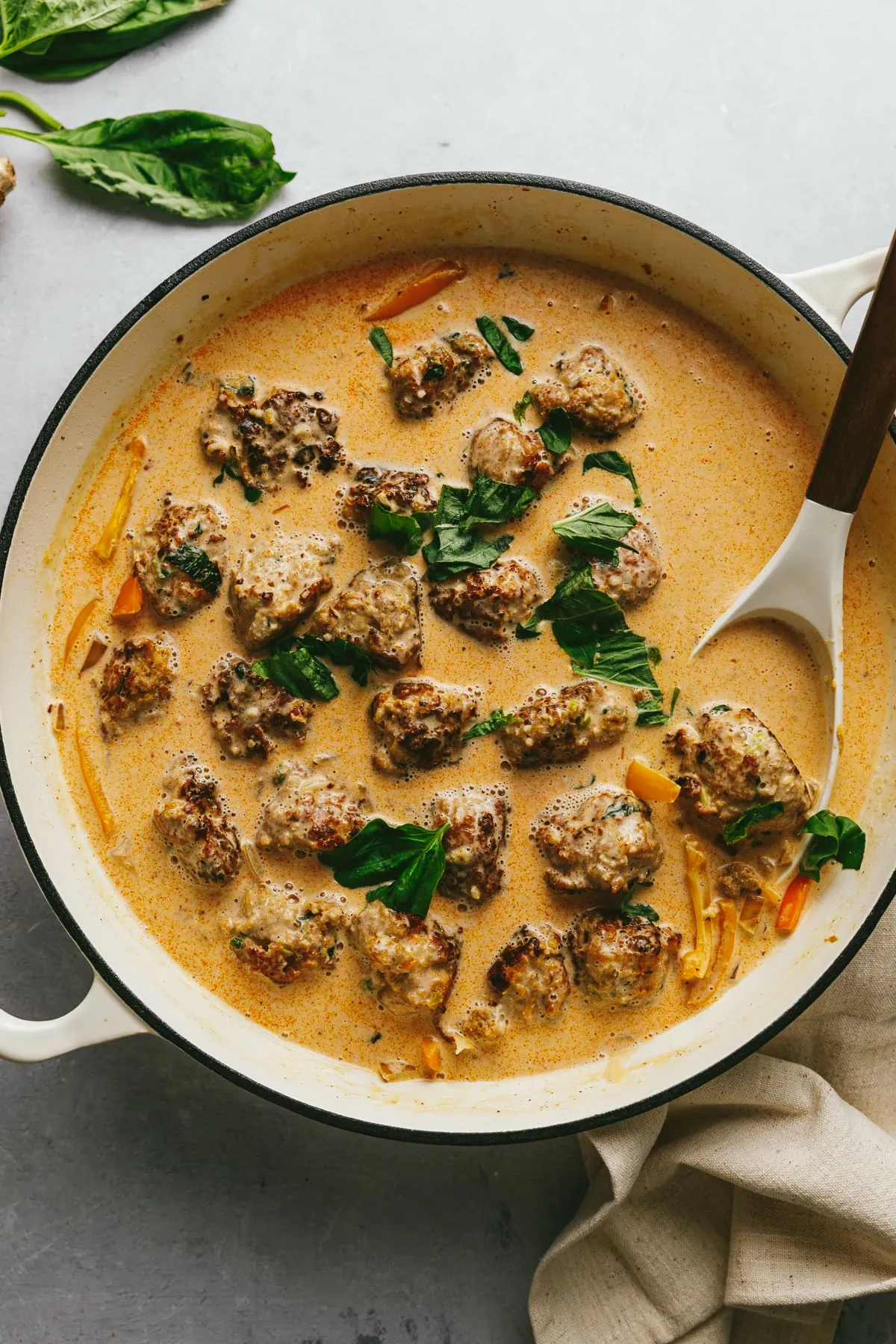 Overhead image of turkey meatballs in red curry sauce with a serving spoon.