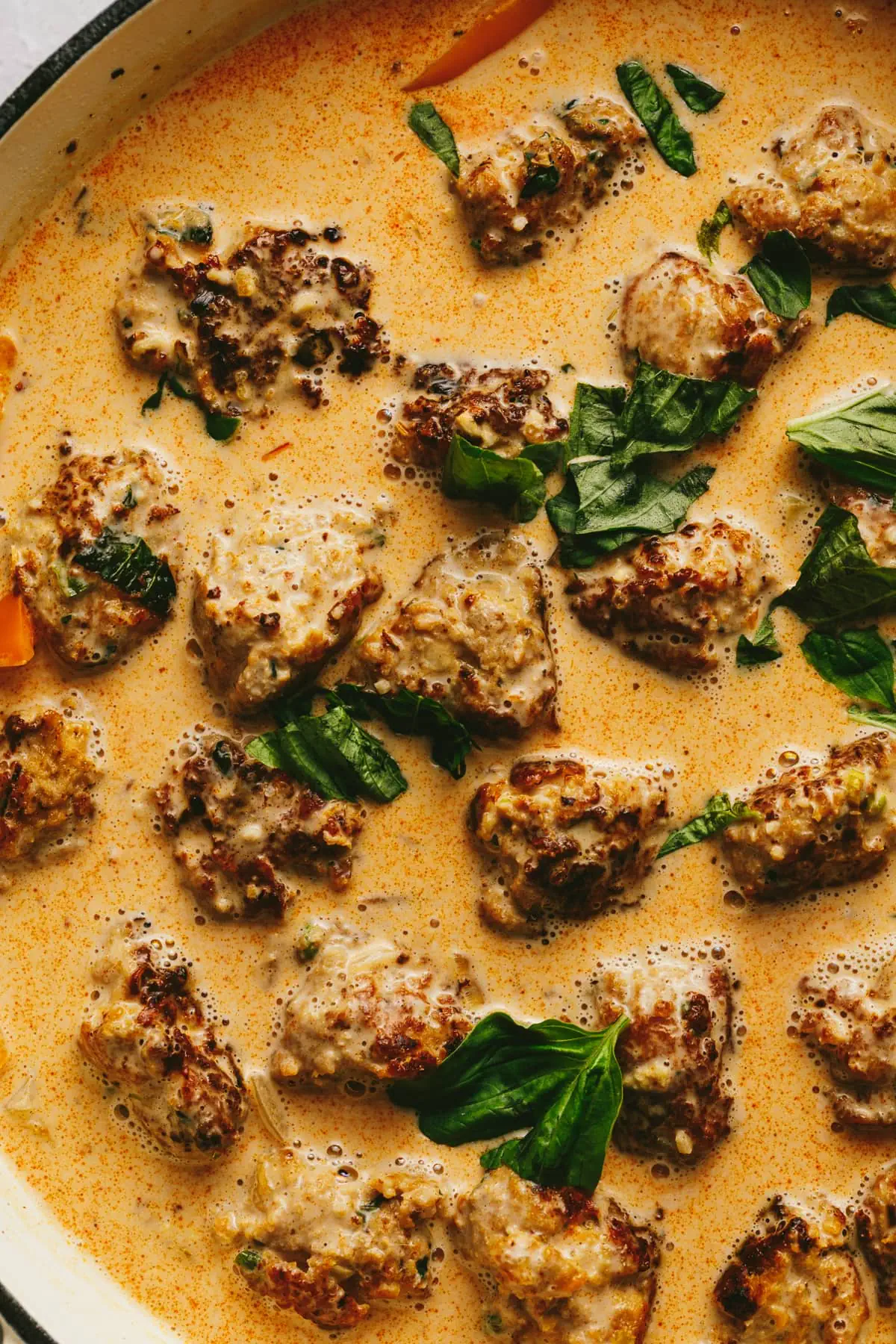 Closeup of keto turkey meatballs in the curry sauce with fresh basil.